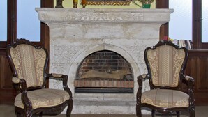 A fireplace with two ornate chairs in front. - Las Mercedes Hostal Residencial (Arequipa)