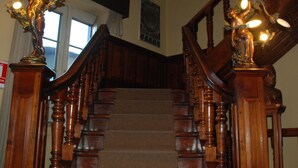 A wooden staircase with ornate railings and wall-mounted lights. - Las Mercedes Hostal Residencial (Arequipa)