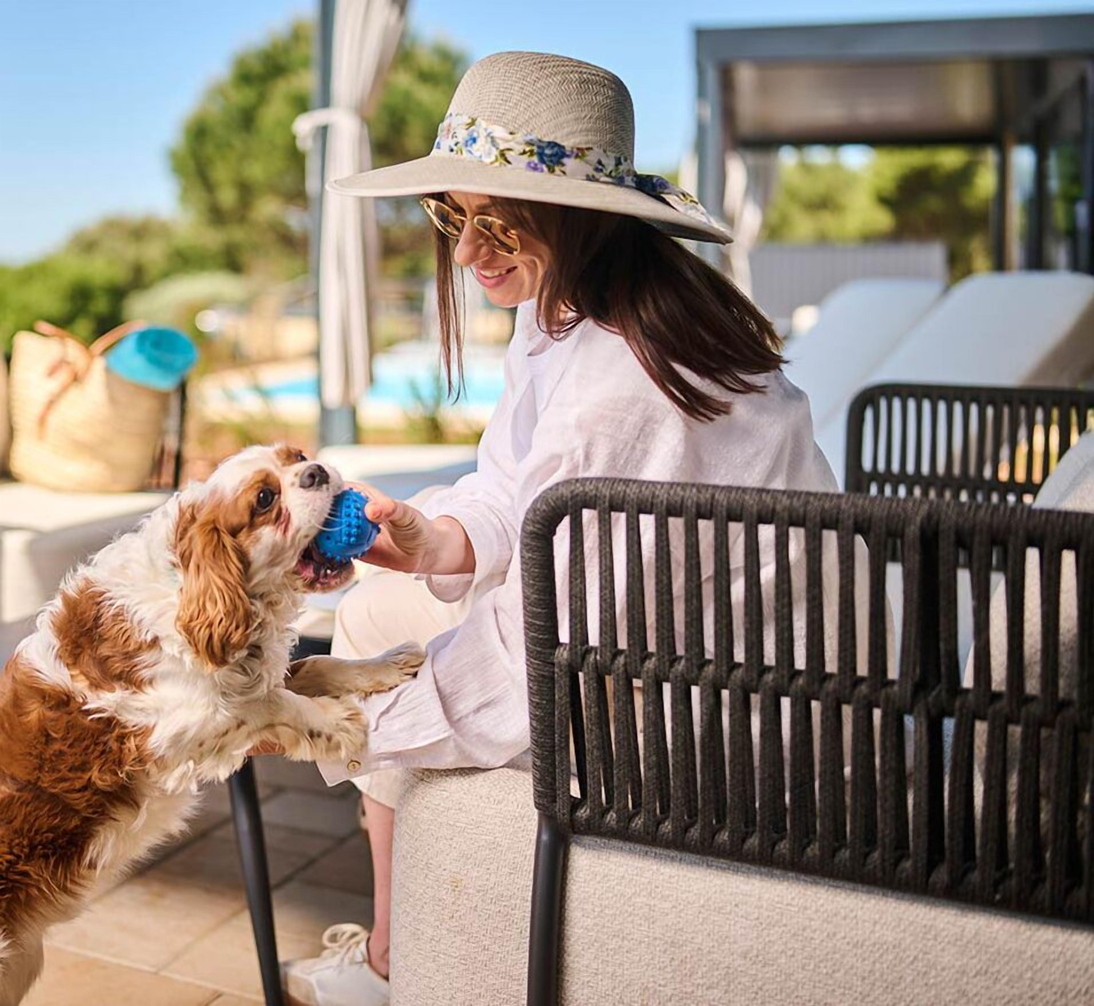 A person sitting on a chair outdoors, holding a dog.