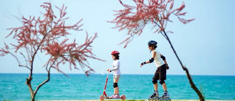 Two people rollerblading near a body of water with trees in the background.