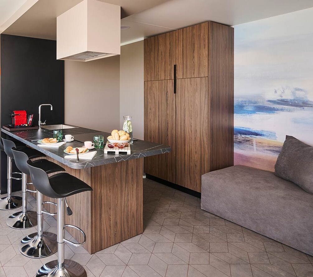 Une cuisine moderne avec un coin bar, des meubles en bois et un canapé gris.