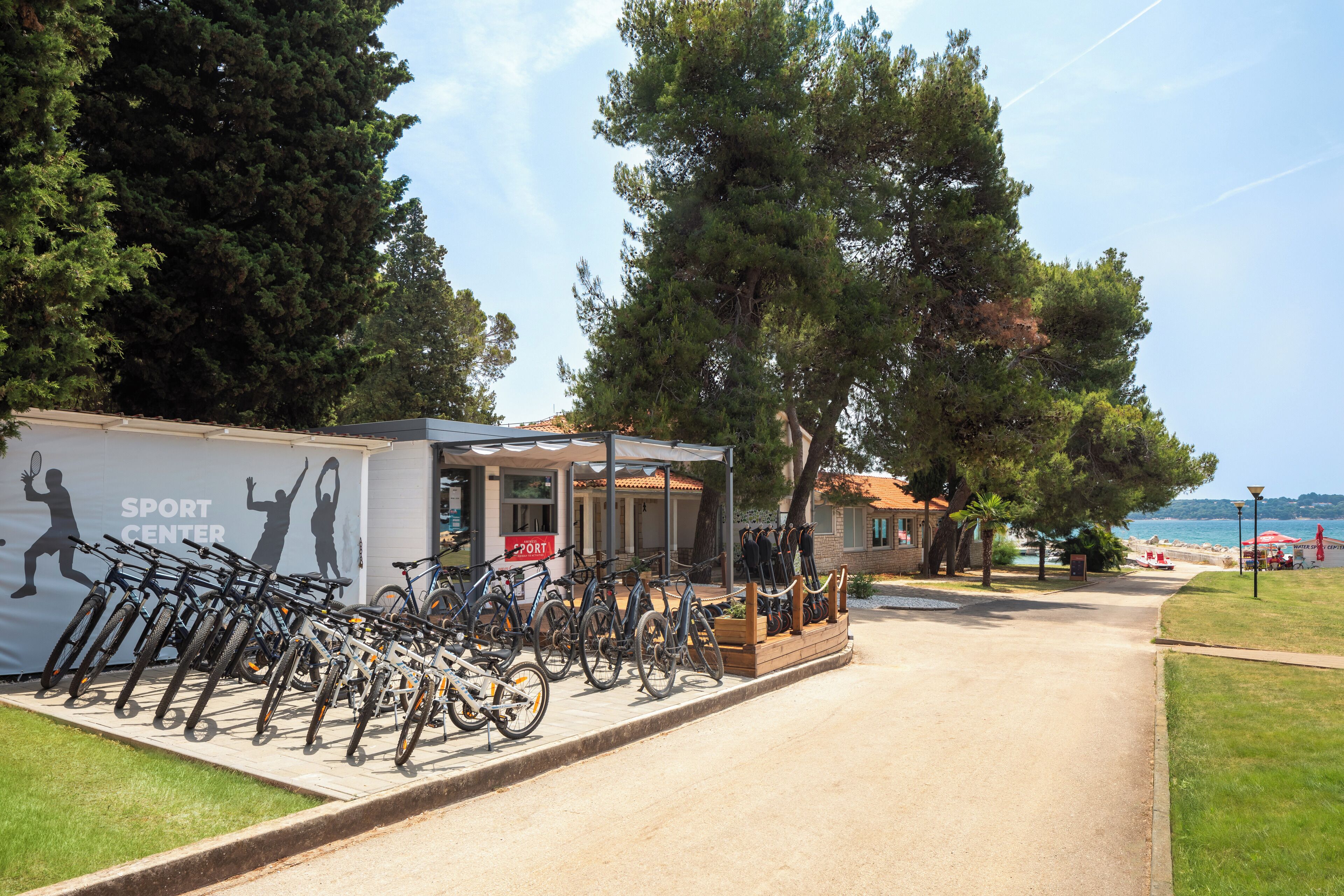A bike rental station with bicycles parked in front of a building labeled "SPORT CENTER".