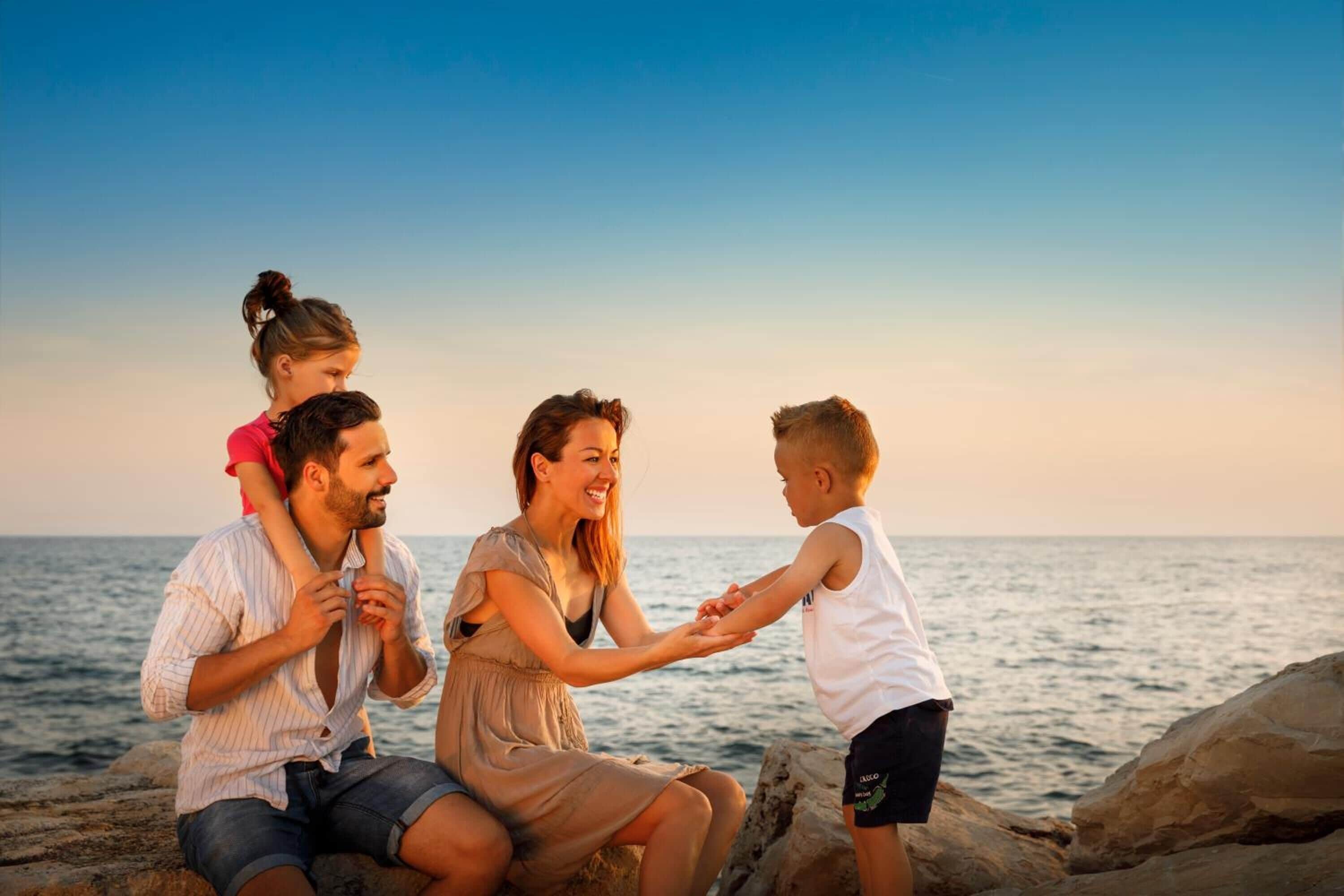 Eine vierköpfige Familie an einem Strand bei strahlendem Himmel.