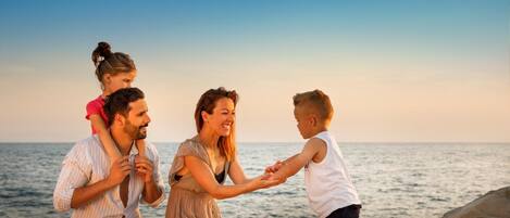 Eine vierköpfige Familie an einem Strand bei strahlendem Himmel.