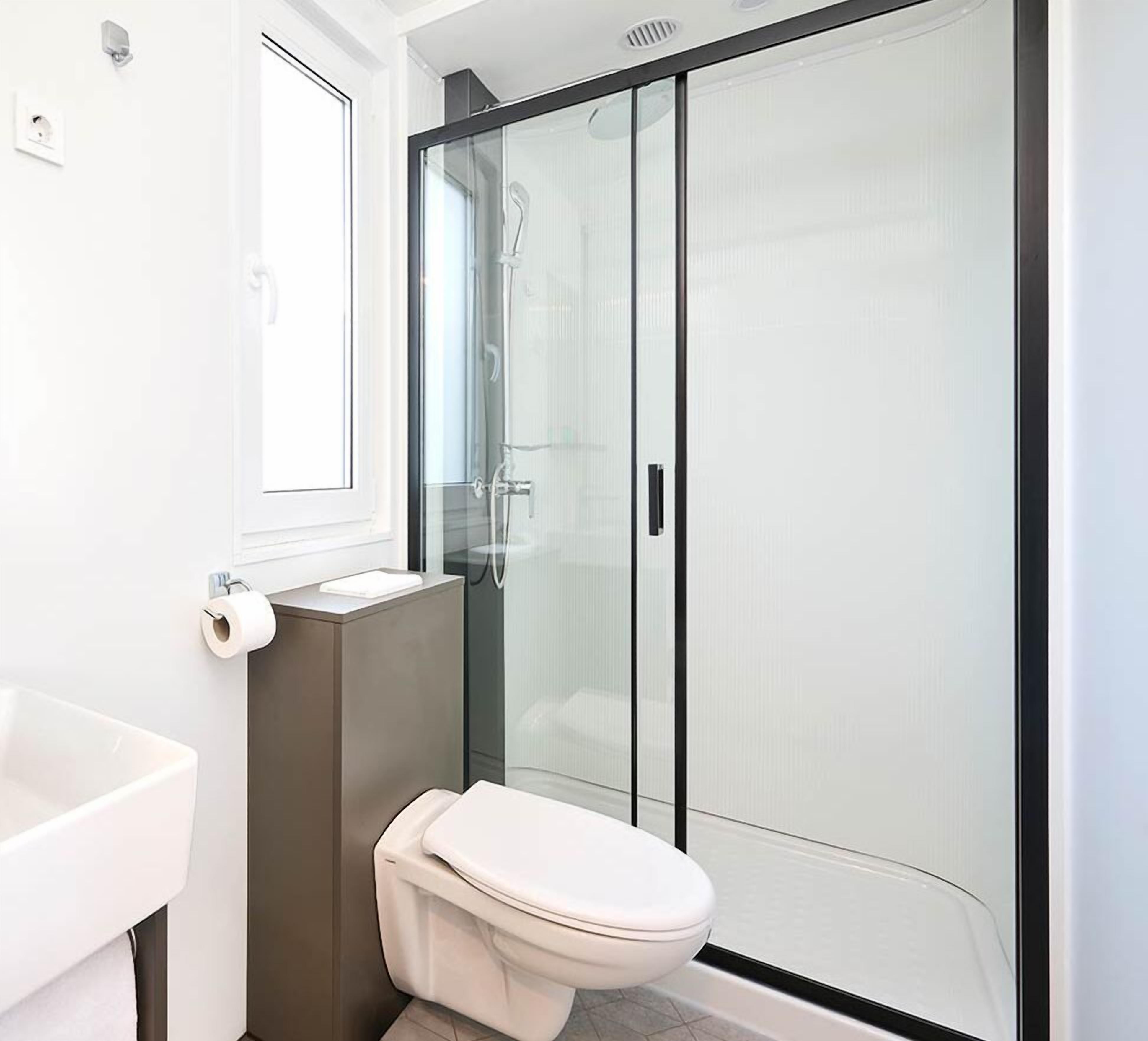 A modern bathroom with a toilet, sink, and glass-enclosed shower.
