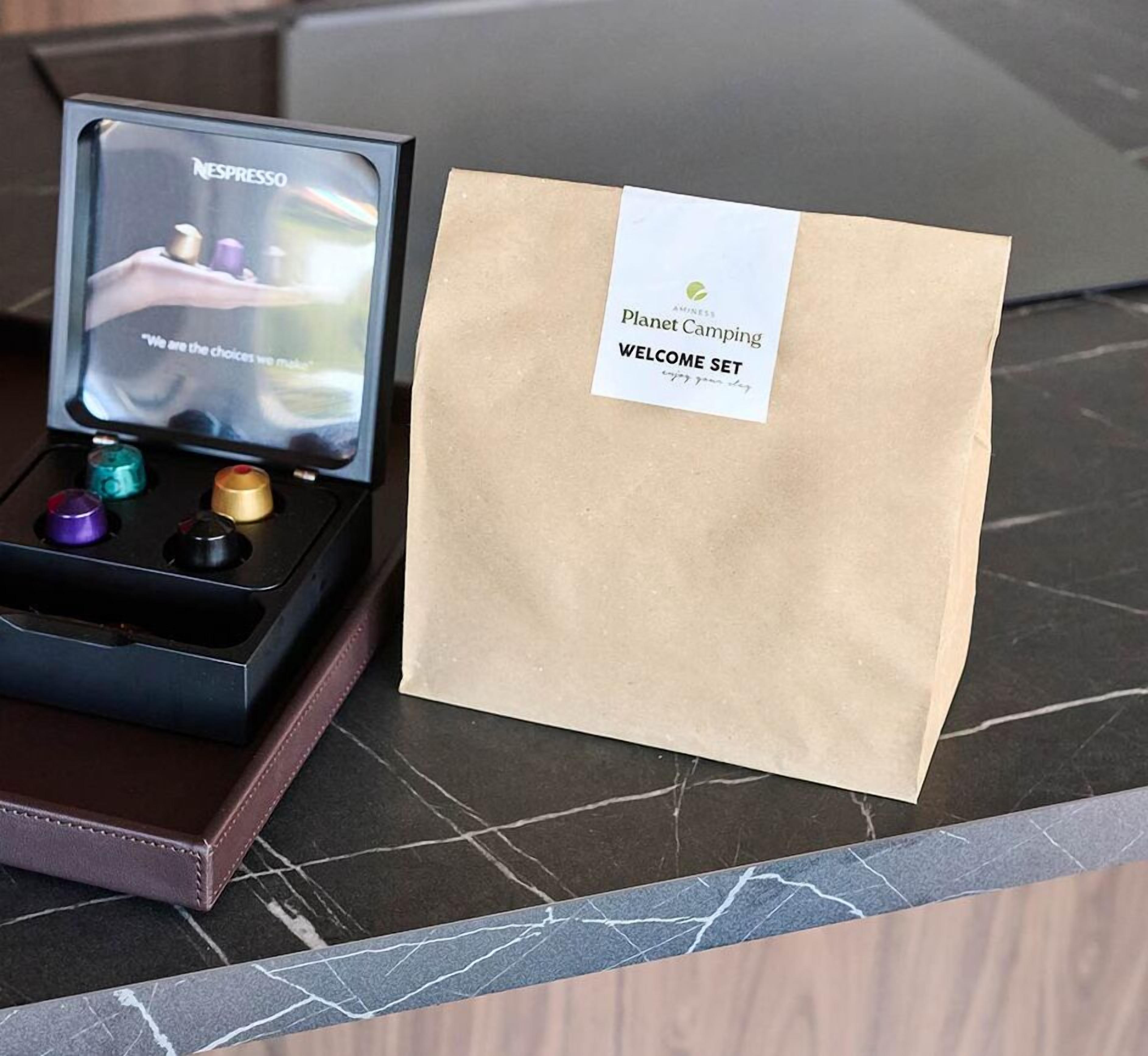 Une machine à café dotée d’un écran Nespresso et d’un ensemble d’accueil Planet Camping, le tout posé sur un plan de travail en marbre.