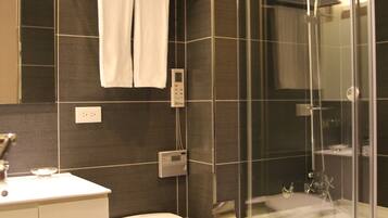 Une salle de bain moderne comprenant des toilettes, un lavabo, une douche à l’italienne et un porte-serviettes.