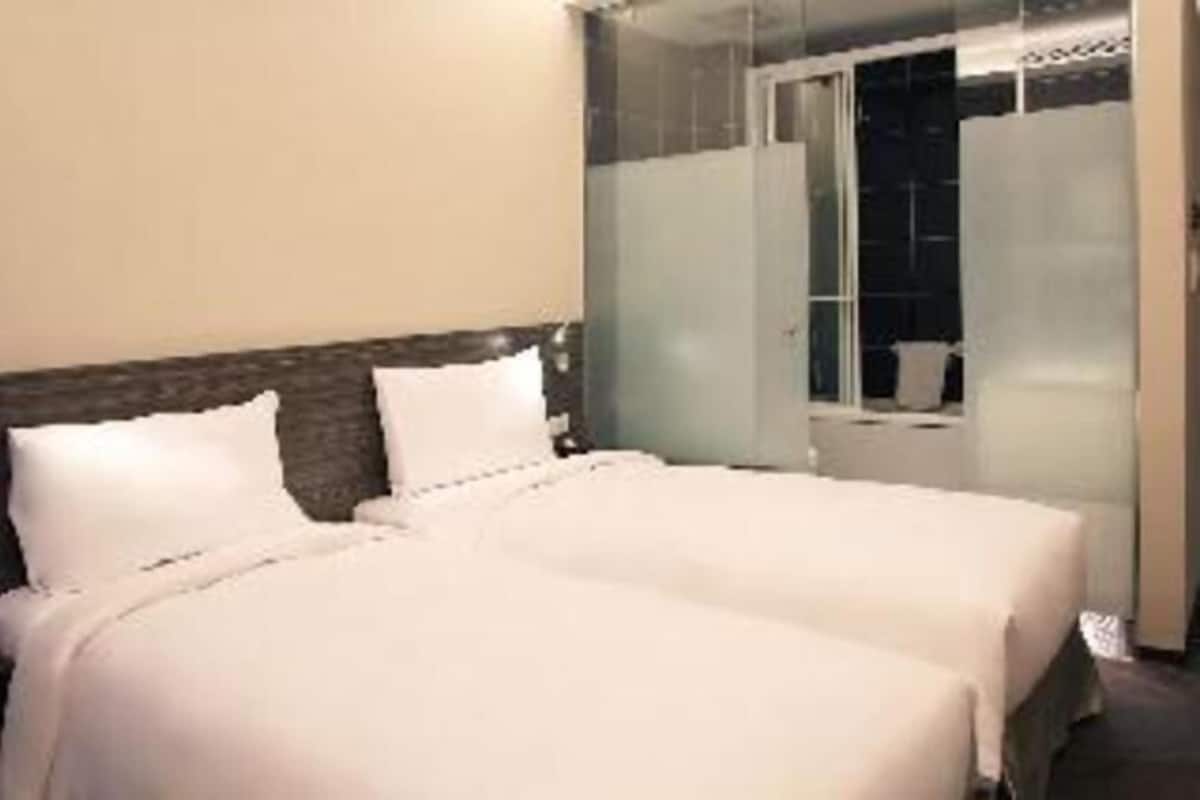 A hotel room with a bed, a window, and a door.