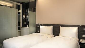 Habitación de hotel con dos camas, un armario, un espejo y un teléfono junto a la cama.