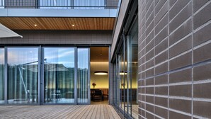 A modern building with large glass doors, a wooden deck, and a brick wall. - Oranda Village (Rogaska Slatina)