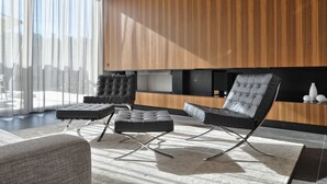 Ein modernes Wohnzimmer mit einer Couch, einem Hocker und einem schwarzen Ledersessel.