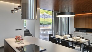 Eine moderne Küche mit einer zentralen Kochinsel, Essbereich mit einem Tisch für sechs Personen und Blick auf eine Terrass.