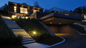 Ein modernes, zweistöckiges Haus mit einer Treppe zum Eingang, umgeben von gepflegter Bepflanzung.