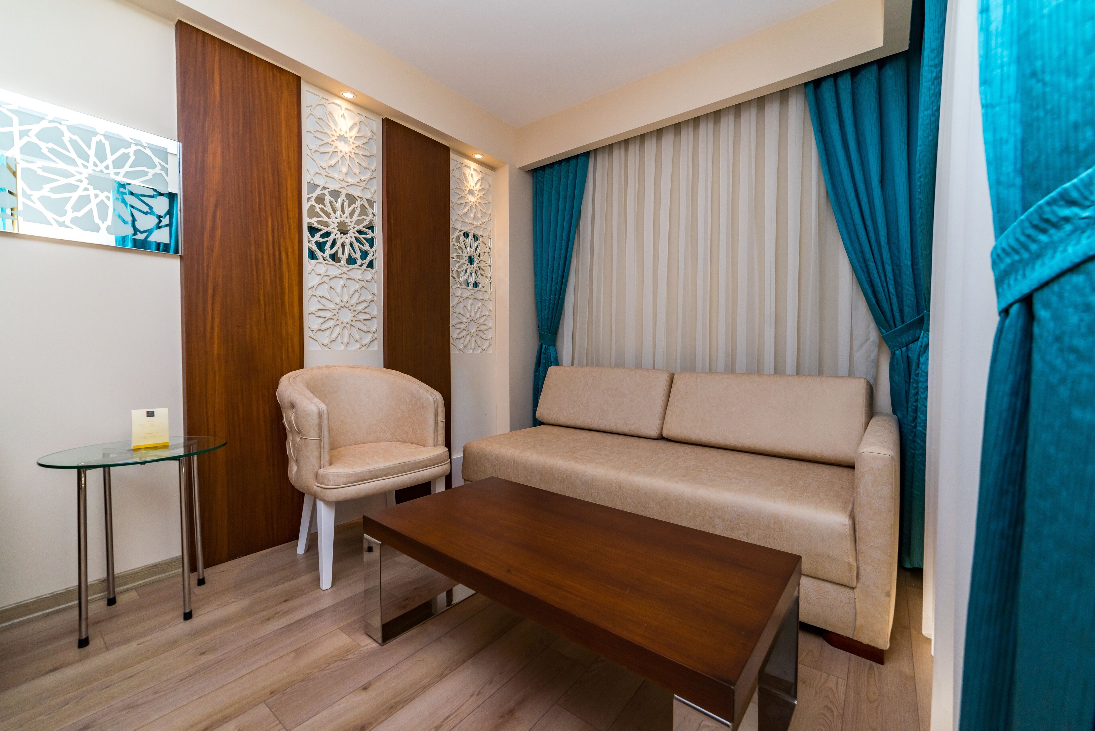 Ein modernes Wohnzimmer mit einem beigefarbenen Sofa, einem Holztisch, einem Glastischchen, einem beigefarbenen Sessel und dekorativen Wandverkleidungen.