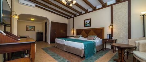 A hotel room with a large bed, a desk, a chair, a small table, and a ceiling fan.