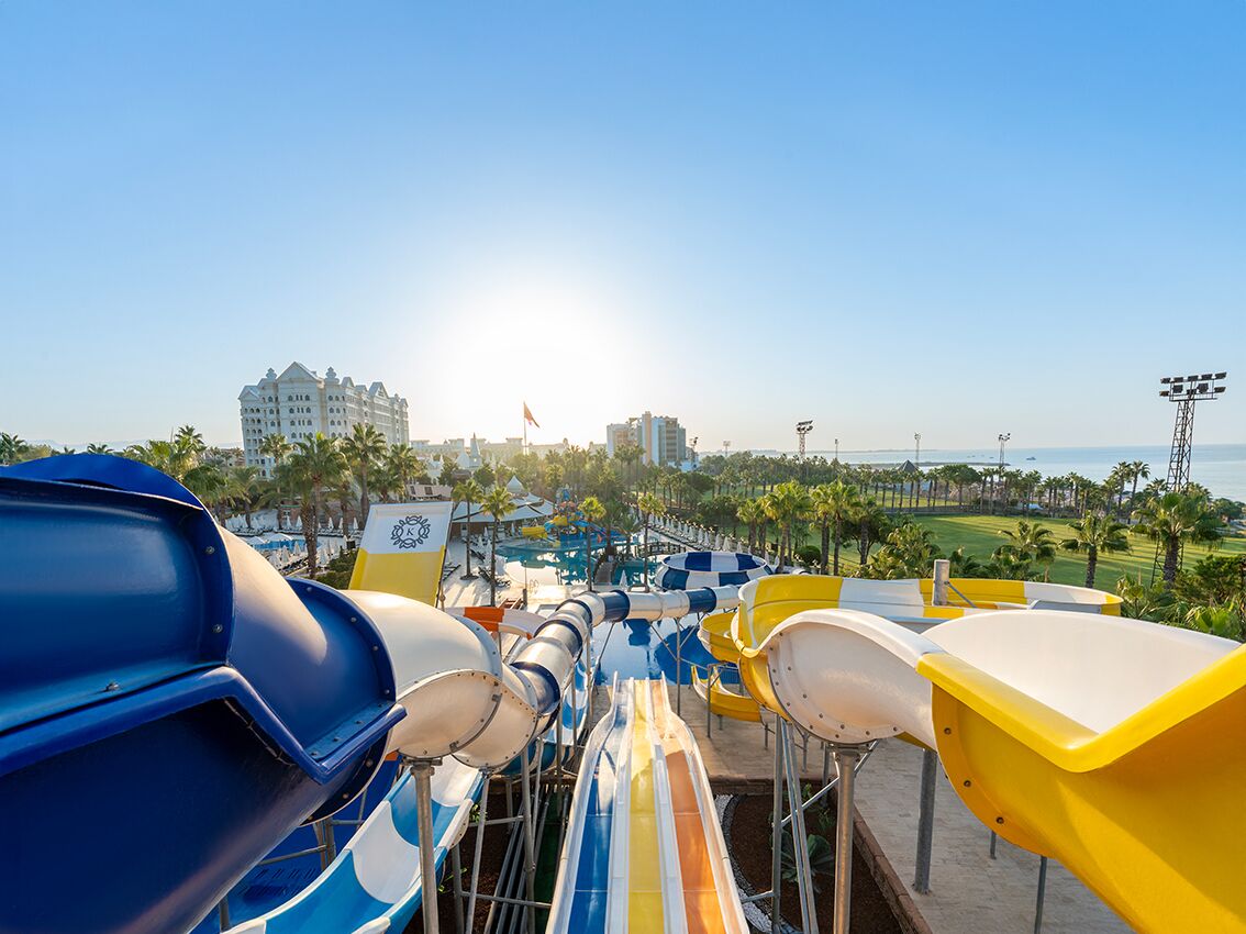 A water park with multiple slides and a view of a hotel and beach in the background.