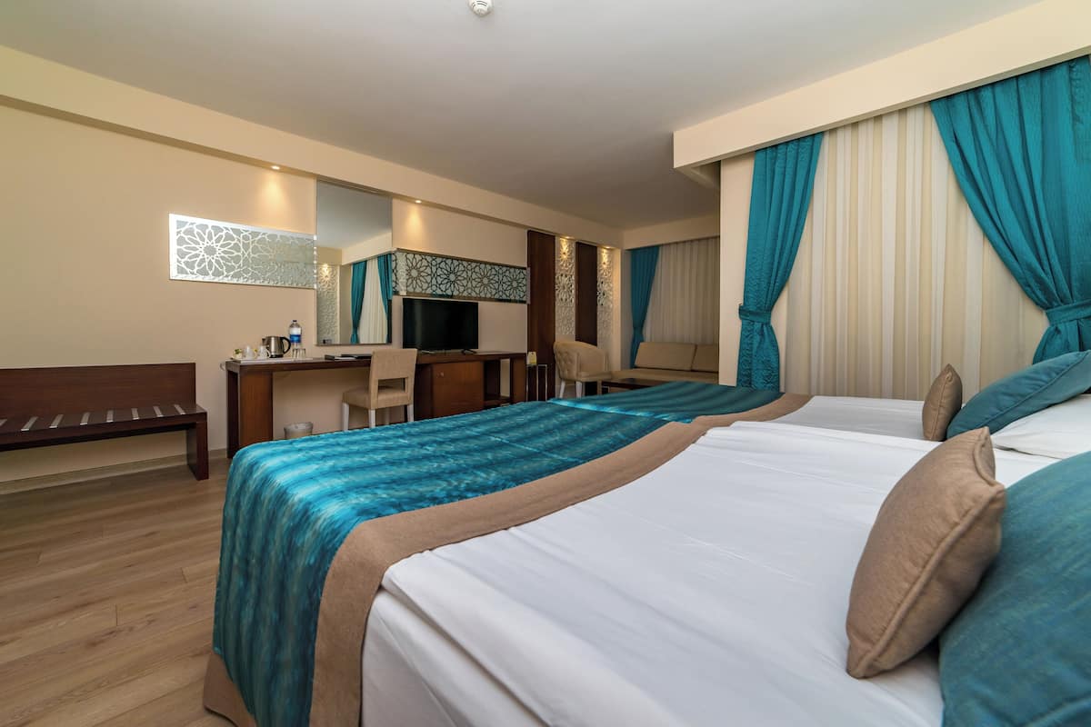 A hotel room with two beds, a desk, a chair, a TV, and a mirror.