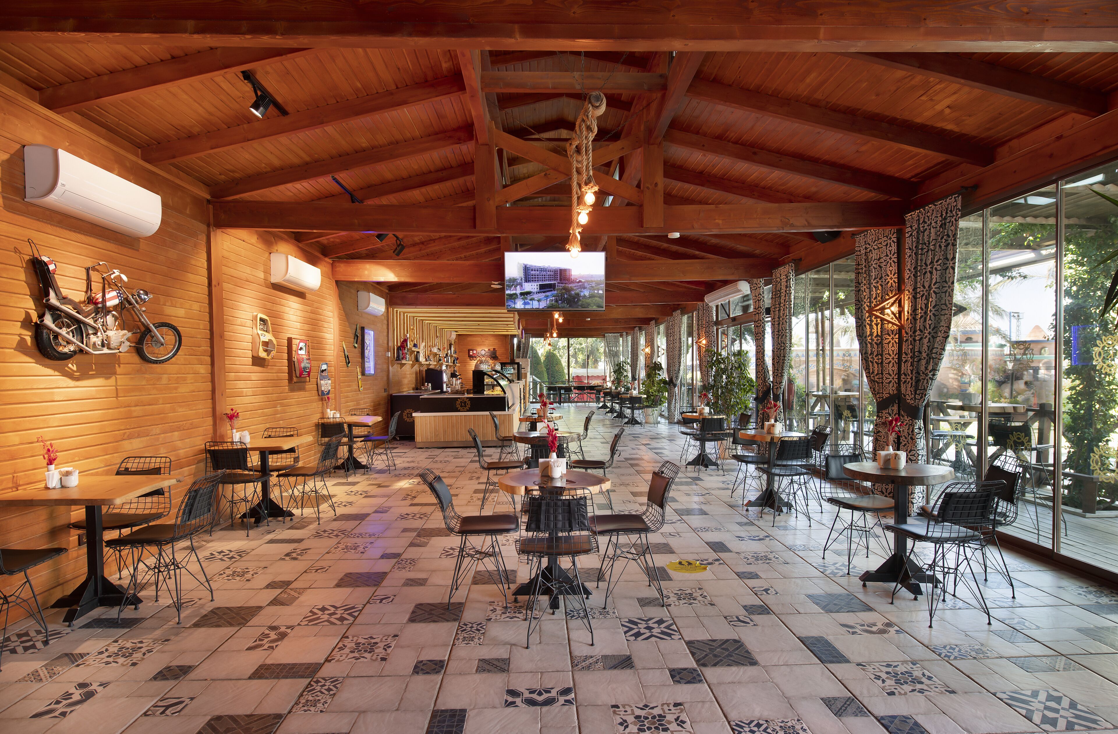 Un vaste espace intérieur doté de poutres apparentes en bois au plafond, d’un revêtement de sol en carrelage et de nombreuses tables et chaises.