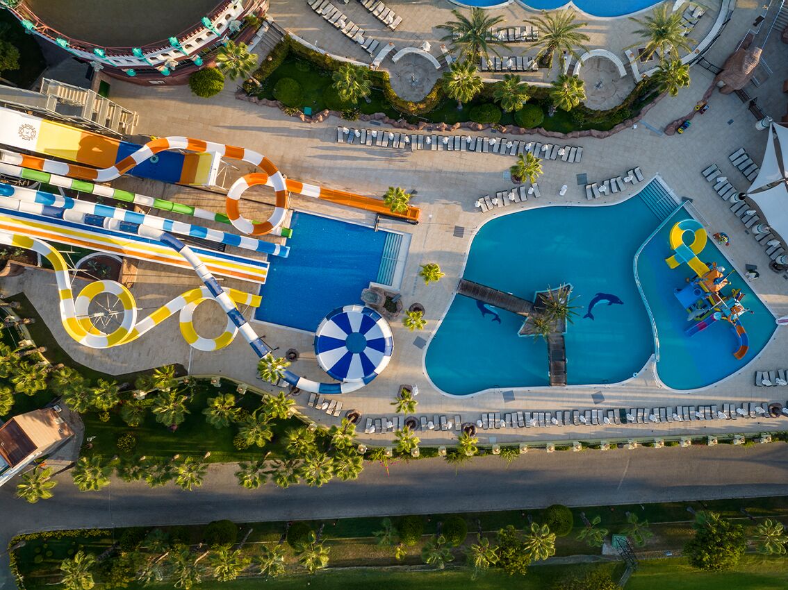 Vista aérea de un parque acuático con múltiples piscinas, un río lento y una piscina de olas.
