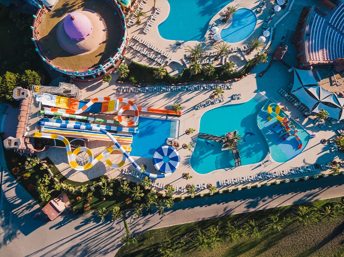 An aerial view of a water park with multiple pools, a wave pool, and a lazy river.