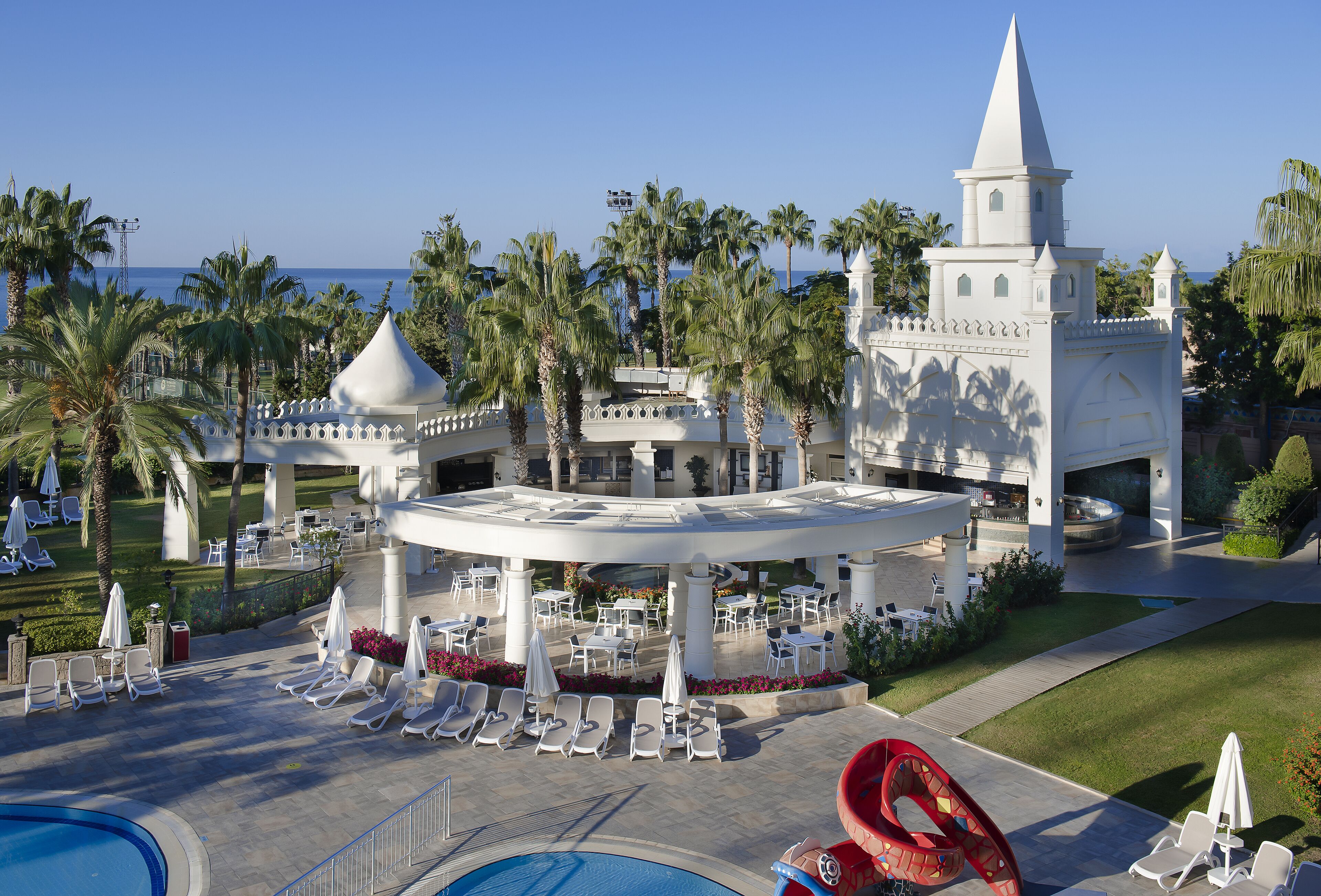 A resort with a pool, lounge chairs, and a castle-like building.