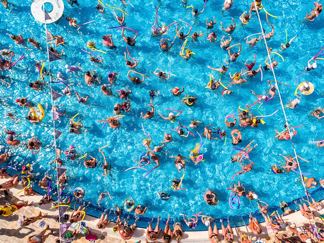 Une piscine où plusieurs personnes pratiquent diverses activités aquatiques.