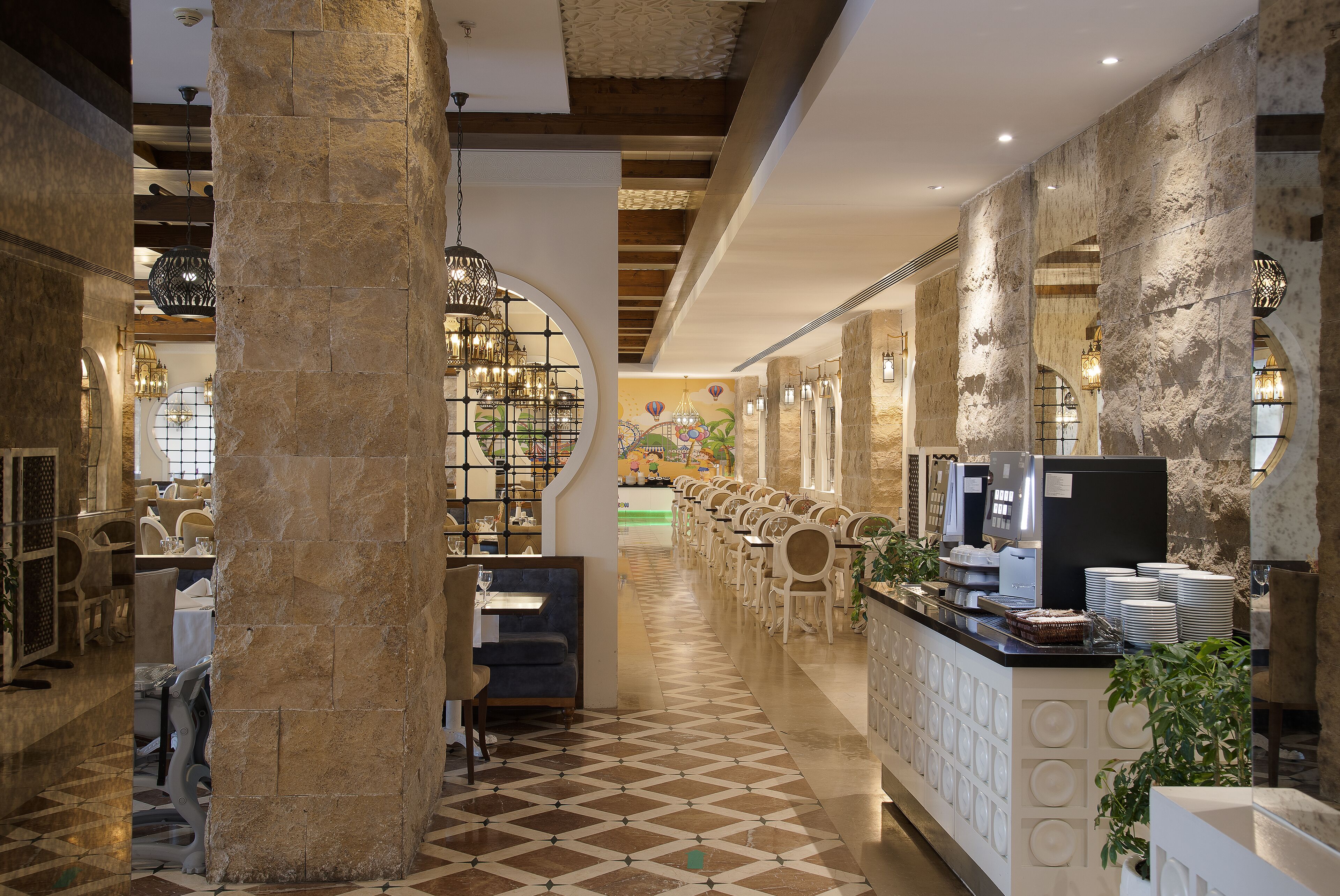 A hotel lobby with a long reception desk, seating area, and a coffee station.
