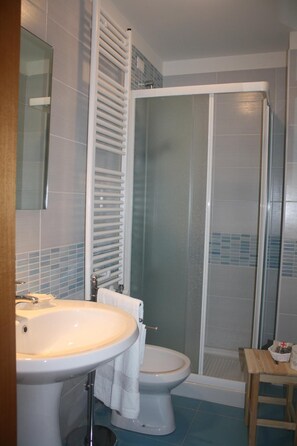 Ein Badezimmer mit weißem Waschbecken, Toilette und Duschkabine.