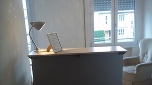 A reception desk with a lamp and a sign, a chair, and a window with a view of buildings.