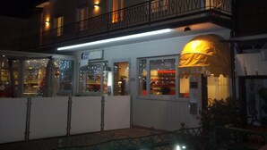 A hotel with a balcony, a covered entrance, and a sign indicating a restaurant.