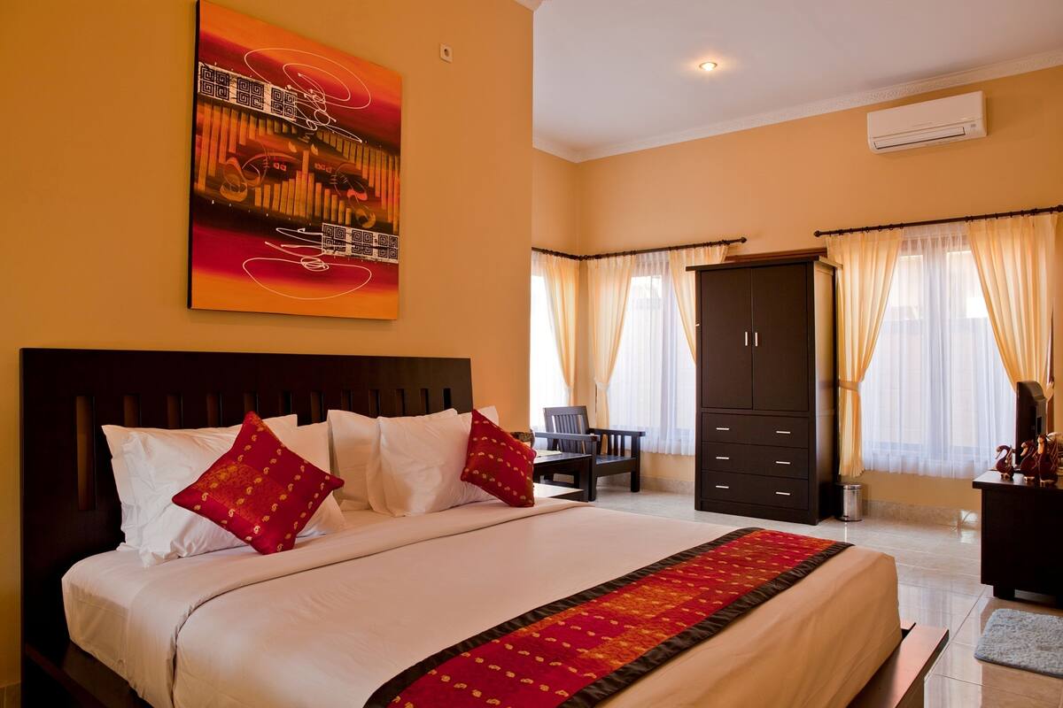 A hotel room with a large bed, a wardrobe, a desk, and a chair.