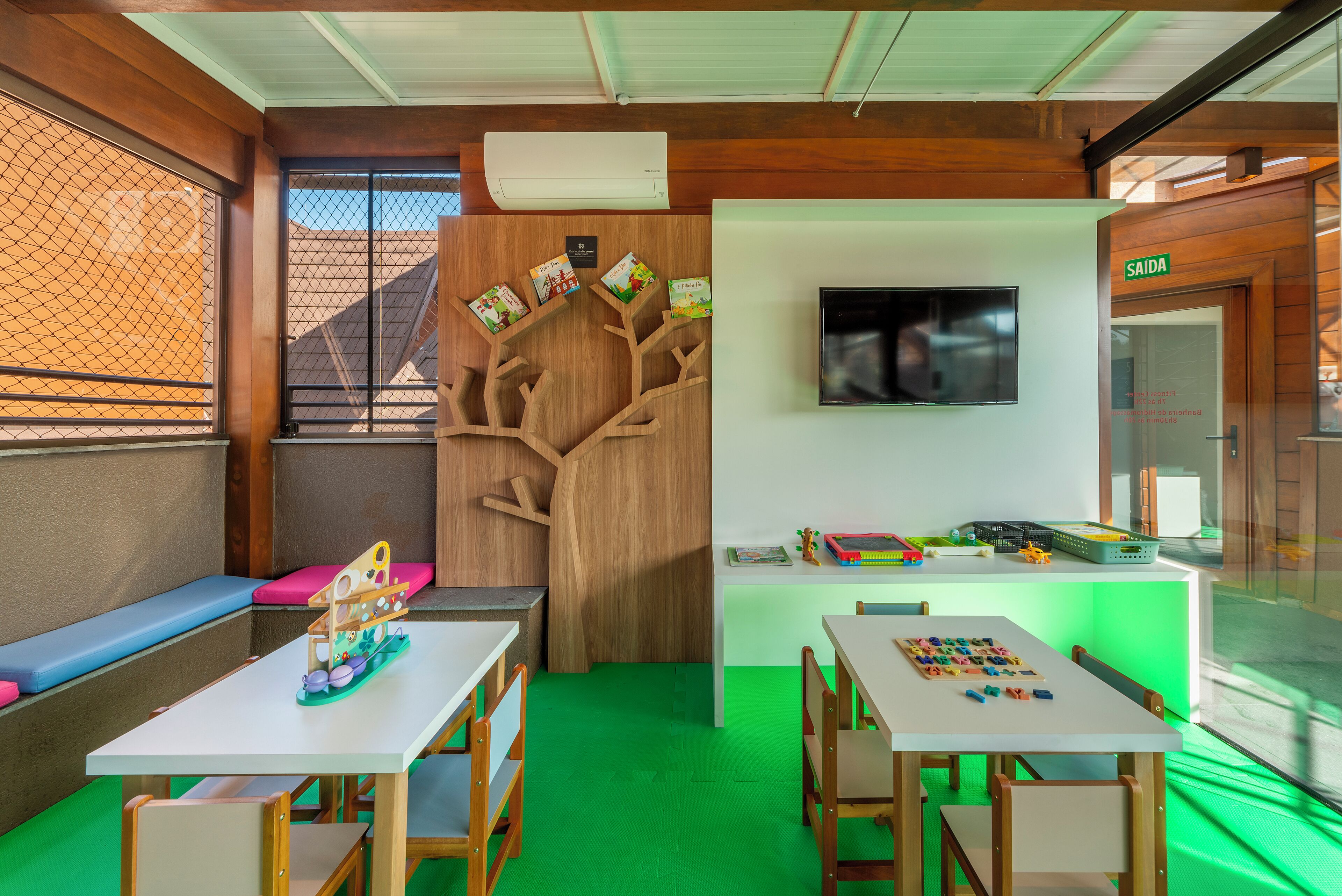 A children's play area with a tree-shaped bookshelf, a television, and a table with educational toys.