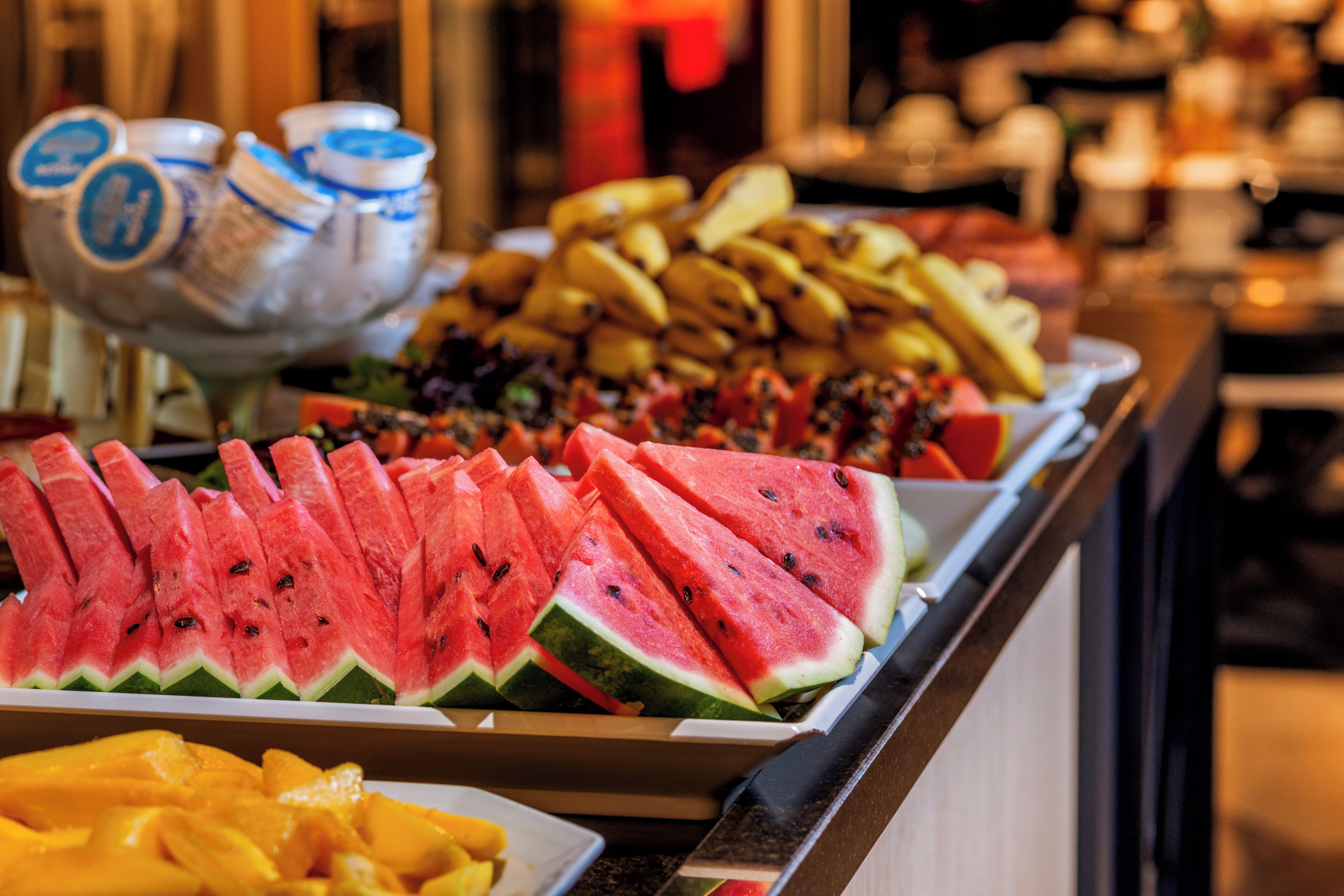 Un bufé con rebanadas de sandía, mangos y otras frutas.