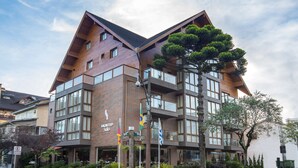 A modern hotel with a distinctive triangular roof, multiple balconies, and a well-maintained garden area. - Hotel Laghetto Stilo Centro (Gramado)