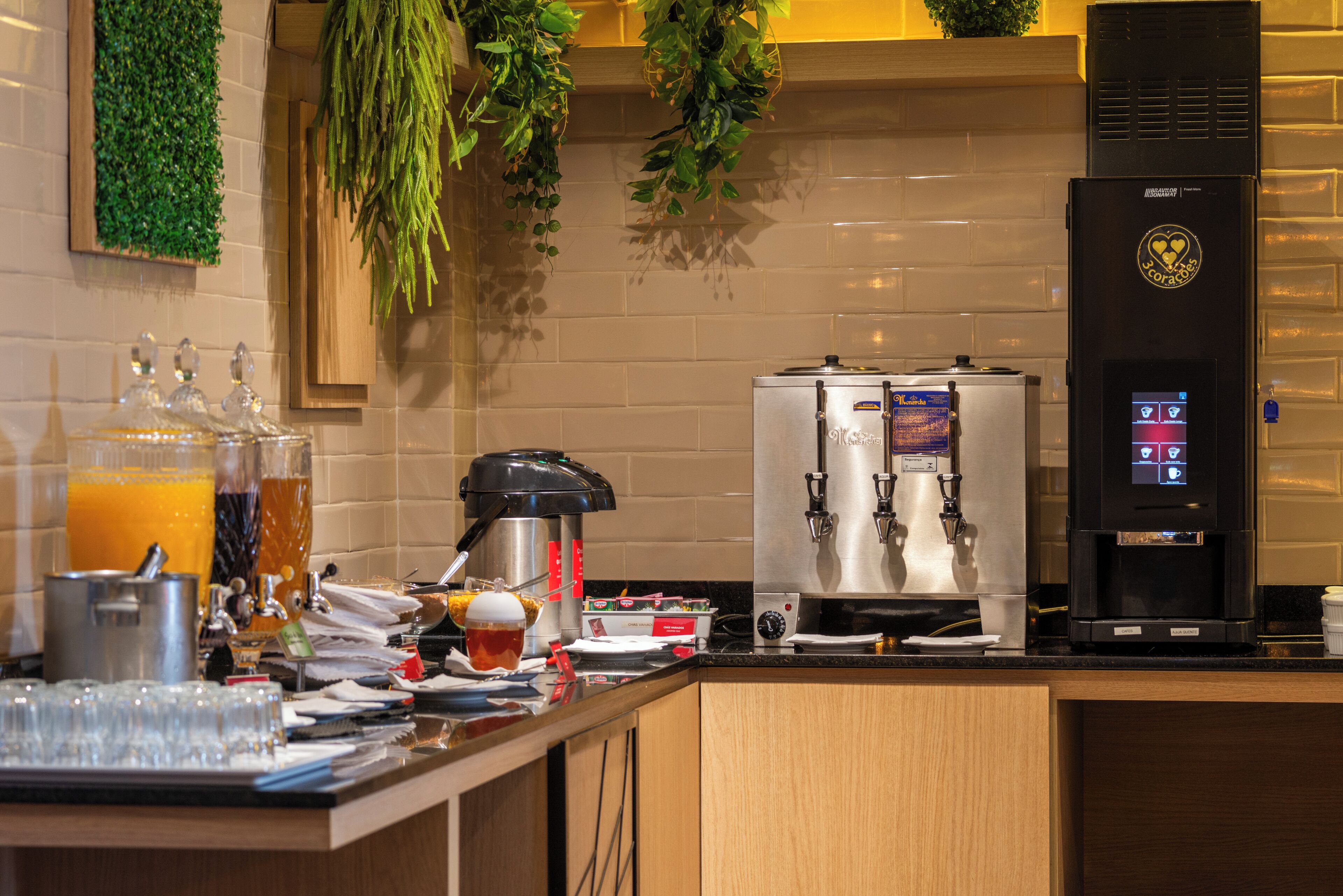 A modern kitchen with a coffee machine, a tea dispenser, and a fruit juicer.