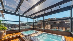 A rooftop terrace with two hot tubs and a wooden deck, overlooking a residential area. - Hotel Laghetto Stilo Centro (Gramado)