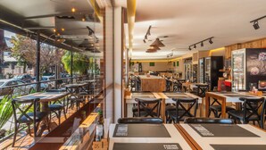 A restaurant with outdoor seating, a bar area, and a view of the street. - Hotel Laghetto Stilo Centro (Gramado)