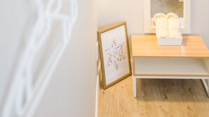 Ein Hotelzimmer mit Holzboden, einem Nachttisch mit Handtuch, einem Spiegel und einer Wandlampe.