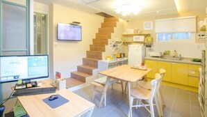 Eine moderne Küche mit einer Holztreppe, einem Essbereich mit Tisch und Stühlen sowie einem Computerarbeitsplatz mit Monitor und Tastatur.