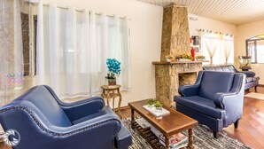 A living room with two blue armchairs, a wooden coffee table, and a stone fireplace. - Pousada das Estrelas Atibaia (Atibaia)