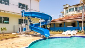 A swimming pool with a blue slide, lounge chairs, and a small garden area. - Pousada das Estrelas Atibaia (Atibaia)