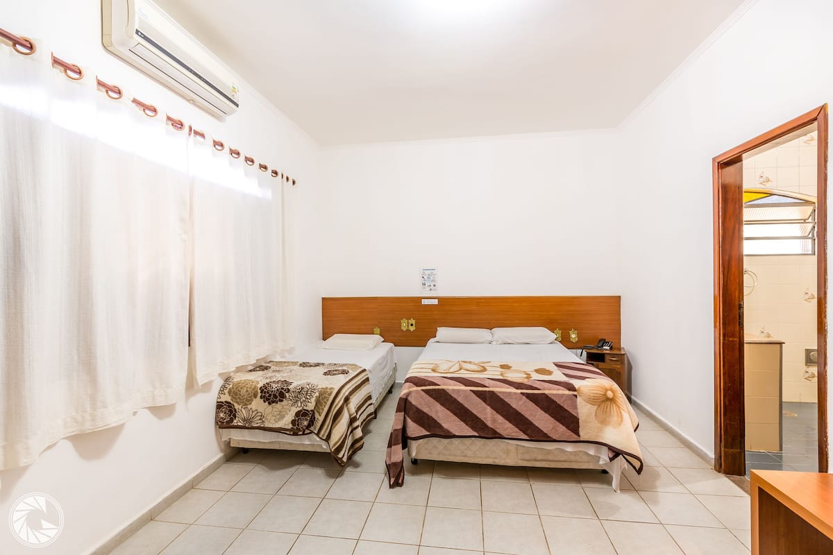 Una camera d'albergo con due letti, una testiera in legno, un piccolo comodino e uno specchio.