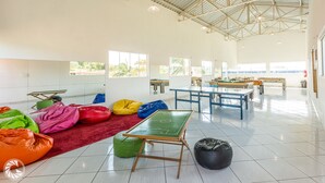 A spacious indoor area with a high ceiling, large windows, and a green table tennis table. - Pousada das Estrelas Atibaia (Atibaia)