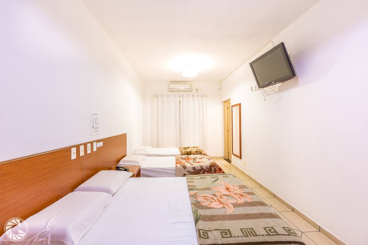 Una camera d'albergo con due letti, televisore e climatizzatore.