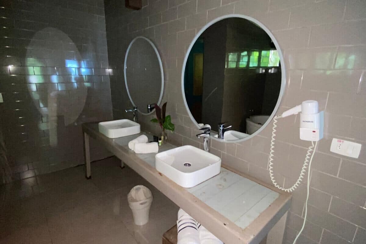 Un baño moderno con dos lavamanos, un espejo grande y un secador de pelo en la pared.
