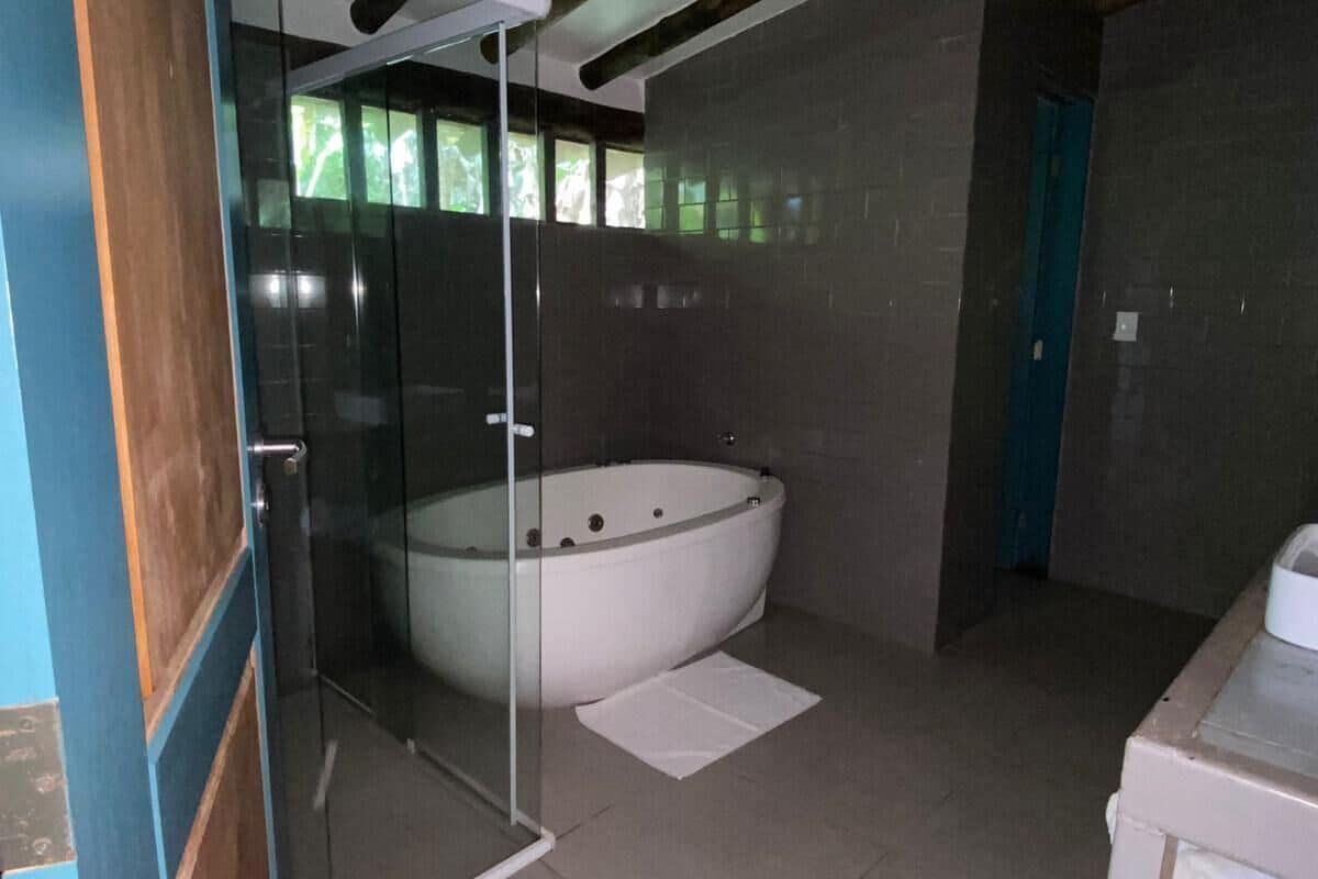 Un baño moderno con ducha a pie con mampara de vidrio, una bañera independiente y una puerta visible.