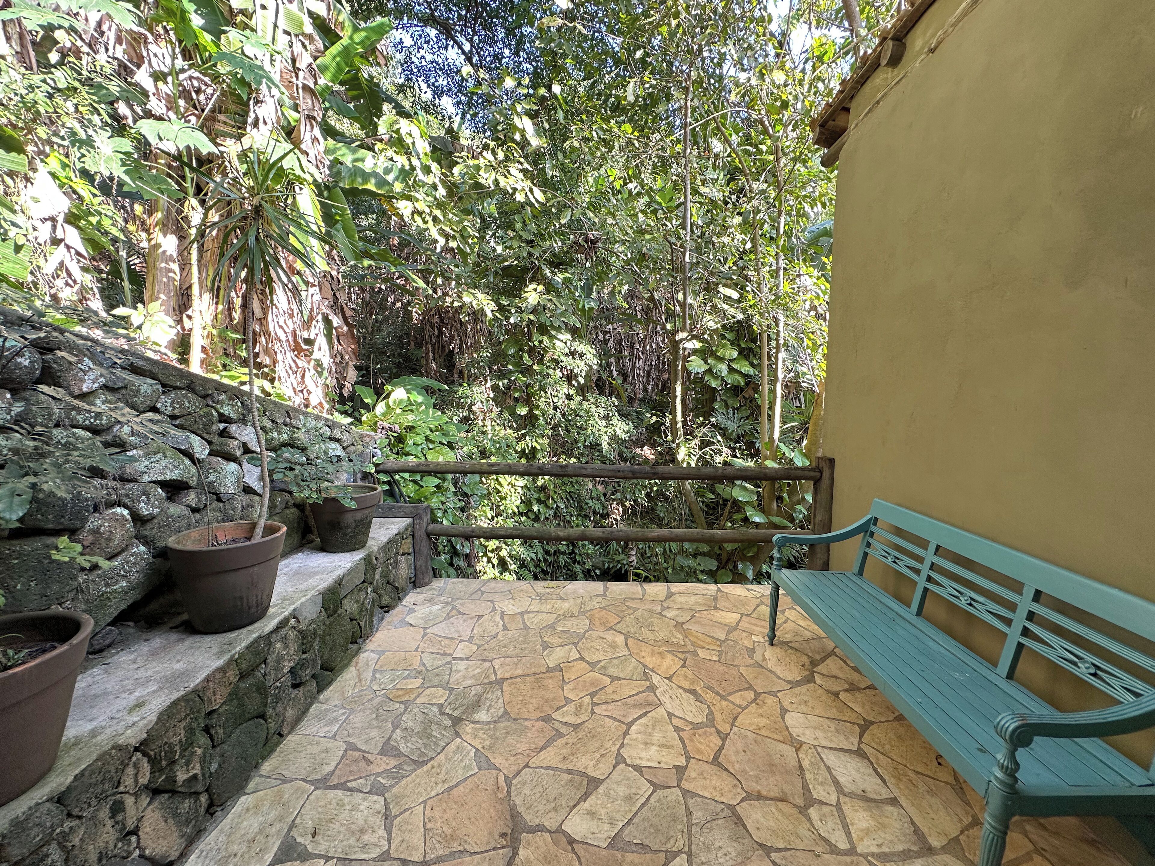 A stone-tiled patio with a wooden bench and potted plants.