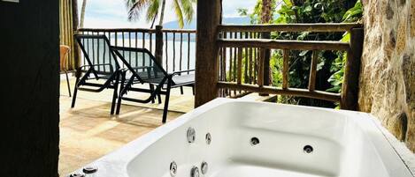 A spa area with a hot tub, wooden deck, and a view of the ocean.