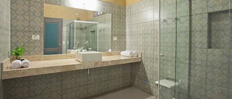 A bathroom with patterned tiles, a large mirror, a sink, and a glass shower enclosure.
