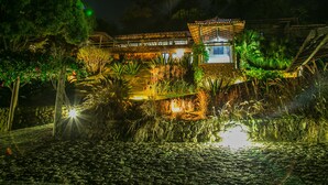 Un edificio bien iluminado con una pared de piedra y un pequeño estanque al frente.